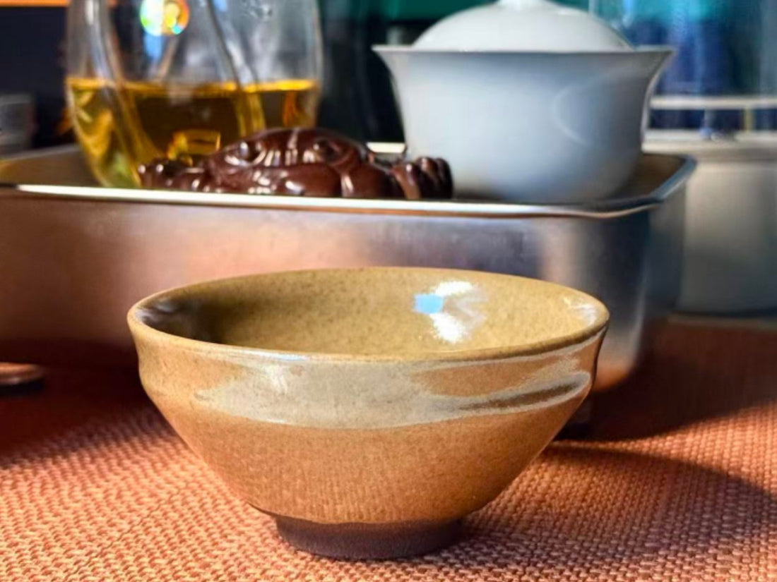 Gaiwan vs Jian Zhan comparison - white porcelain lidded bowl beside a brown glazed tea cup on a gongfu tea table