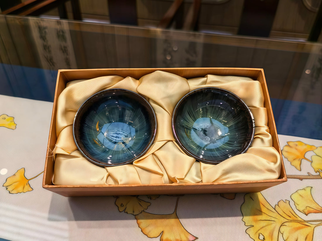 Two blue glazed Jian Zhan cups in a wooden gift box lined with gold silk, ready for holiday gifting